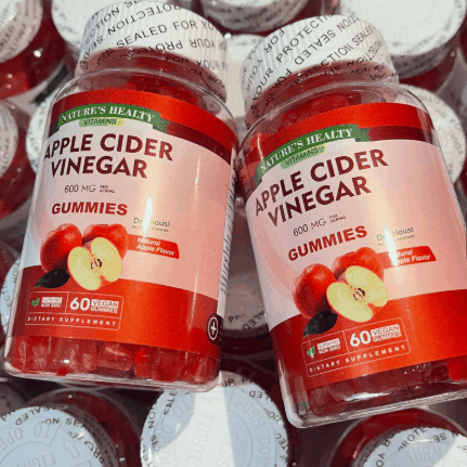 Apple Cider Vinegar Keto Gummies in clear bottles with red and pale pink labels, fruit graphics and sealed caps