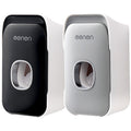 Automatic Toothpaste Squeezer in black and light gray plastic, with a sleek wall-mounted case and oval dispensing opening.