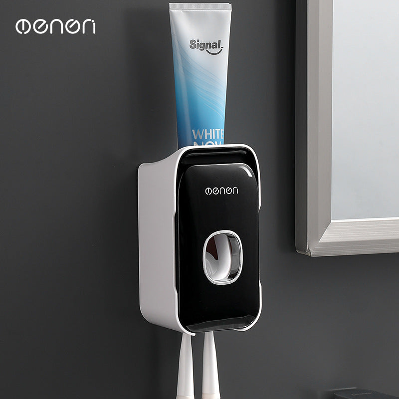Automatic Toothpaste Squeezer in black and white plastic, wall-mounted dispenser with a central press and toothbrush holders