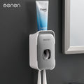 Automatic Toothpaste Squeezer in gray plastic with a white trim, holding a toothpaste tube and two toothbrushes