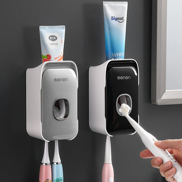Automatic Toothpaste Squeezer in gray and black plastic, with wall-mounted dispensers, central push openings, and toothbrush holders.