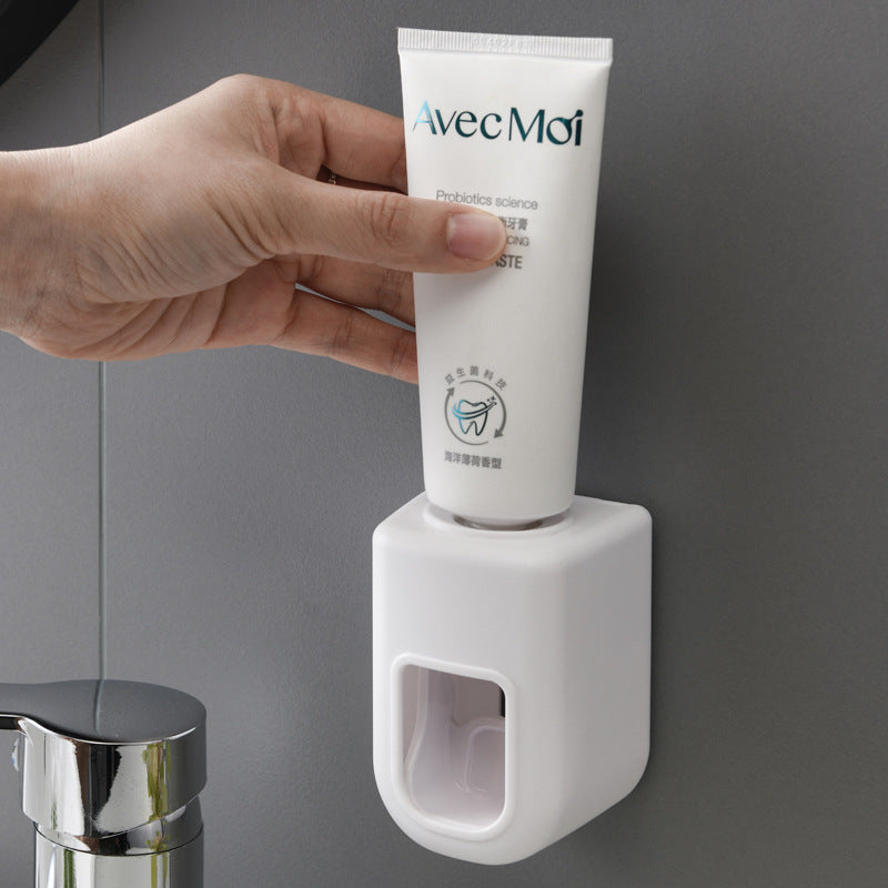 Automatic Wall Mounted Toothpaste dispenser set in white, pale blue and pink plastic, with front dispensing openings and toothpaste tubes.