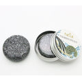 Bamboo Charcoal Shampoo Soap Bar in dark gray with a speckled texture, shown beside an open round metal tin