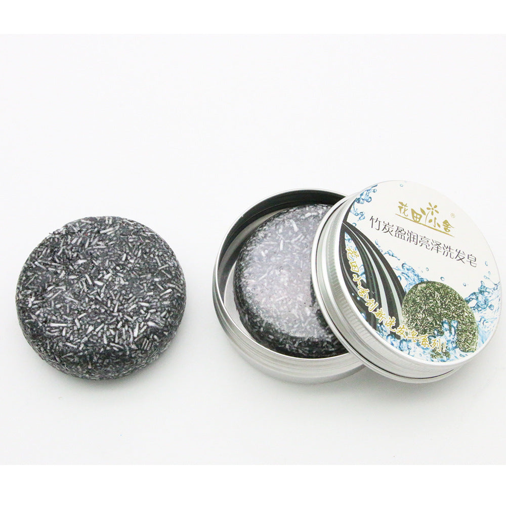 Bamboo Charcoal Shampoo Soap Bar in dark gray with a speckled texture, shown beside an open round metal tin