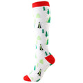 Christmas Compression Socks in white knit with green tree and black figure patterns, red cuff, heel and toe accents