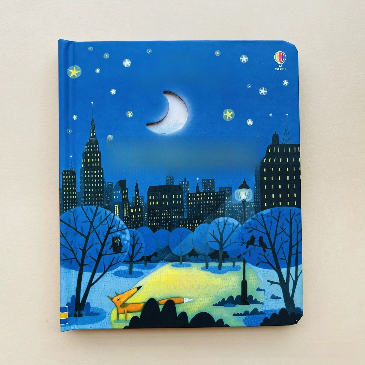 Educational  Picture Books peek-through board book with a blue nighttime cityscape cover, crescent moon cutout, stars, trees and park path.