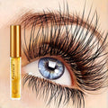 Eyelash serum in a clear tube with a gold cap beside an eye with long, dark, curled lashes