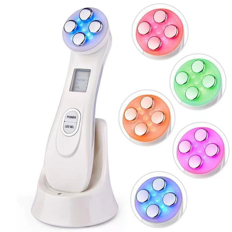 Facial Beauty Device with a glossy white plastic body, charging stand, display, and rounded multicolour LED treatment head
