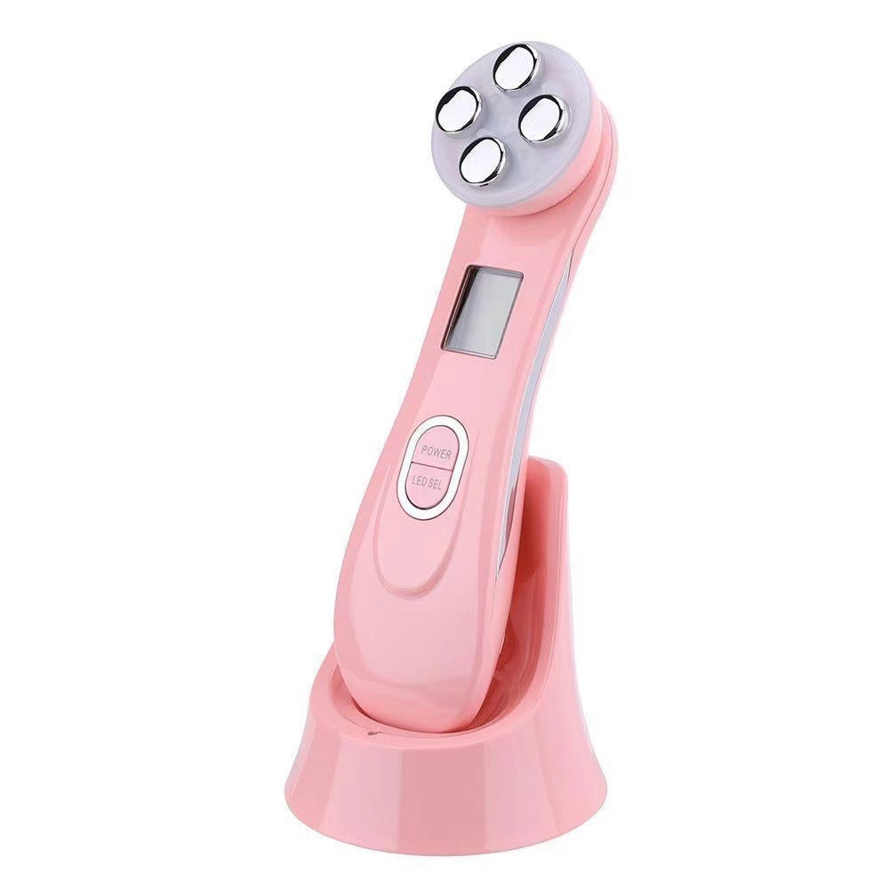 Facial Beauty Device in glossy pink with a rounded four-contact metal treatment head, small display, and matching charging base