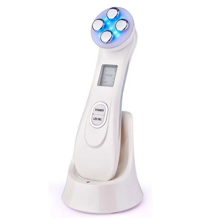 Facial Beauty Device with a glossy white plastic body, charging stand, display, and rounded multicolour LED treatment head

