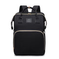 Foldable Baby Bed shown as a black Oxford cloth backpack with beige piping, top handles, shoulder straps and zip pockets