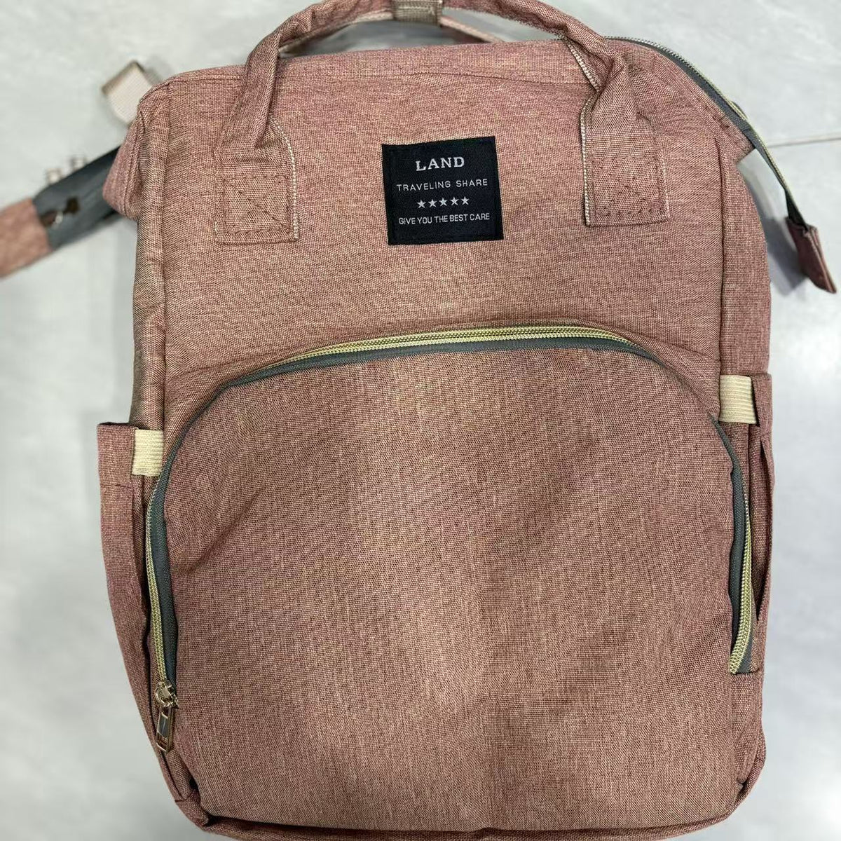 Foldable Baby Bed carrier bag in dusty rose heathered fabric, with top handles, shoulder straps and a front zip pocket
