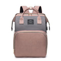 Foldable Baby Bed shown as a two-tone gray and dusty pink fabric backpack with top handles, straps, and zippered pockets