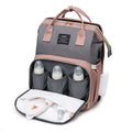 Foldable Baby Bed shown as a gray and dusty pink Oxford cloth backpack with bottle pockets and a fold-down changing mat
