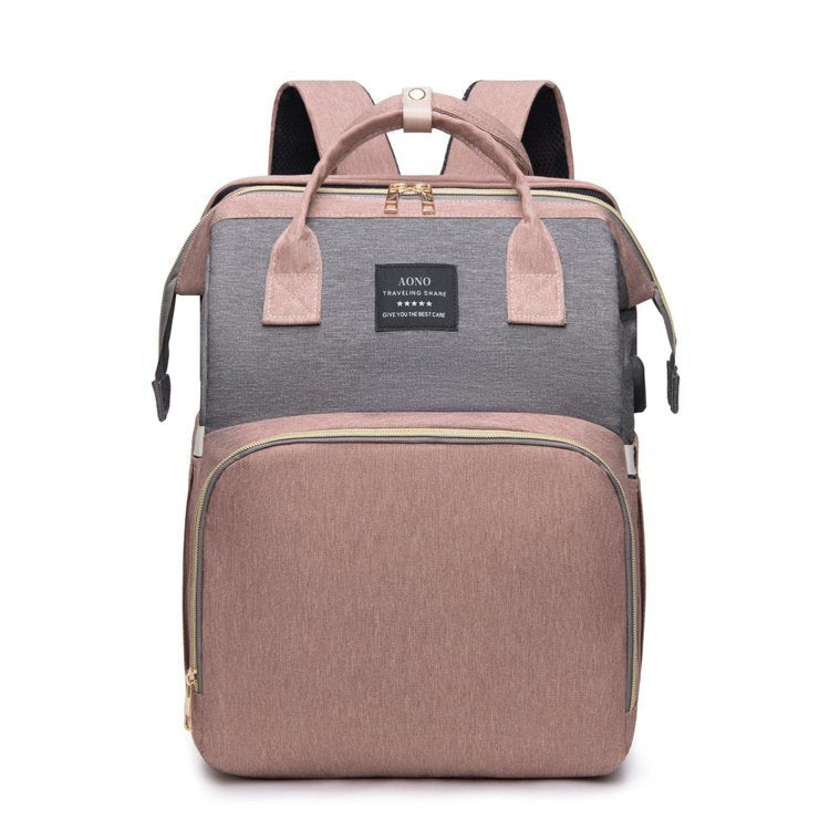 Foldable Baby Bed carrying backpack in pink and gray fabric with dual top handles, shoulder straps and zippered compartments