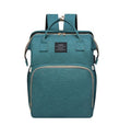 Foldable Baby Bed shown as a teal fabric carry bag with zippered compartments, top handles, and shoulder straps