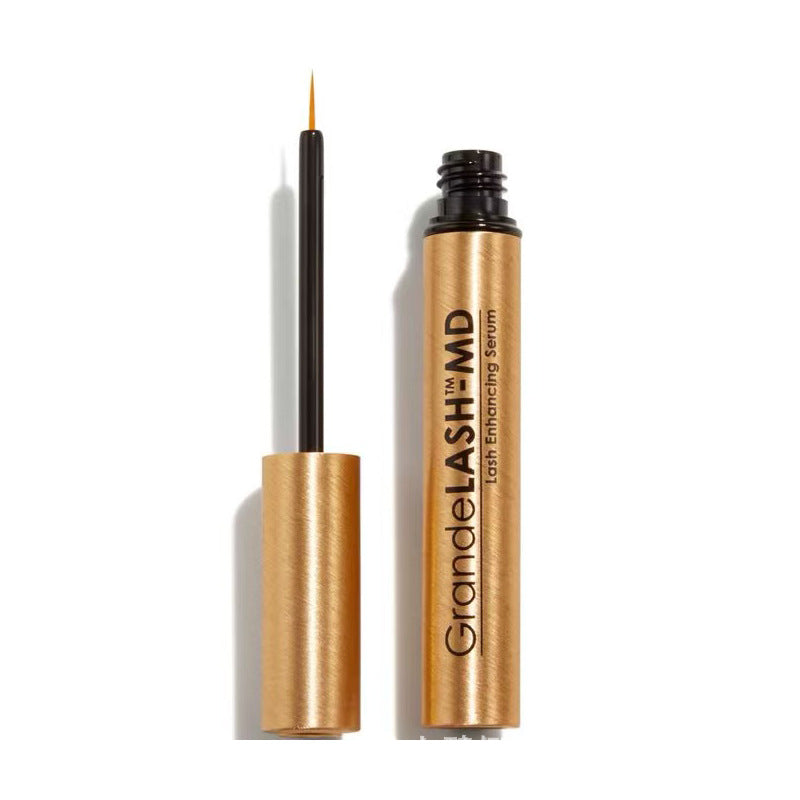 Eyelash enhancing serum in a metallic gold tube with a slim black applicator wand and orange tip, labeled Grande Lash Eyelash