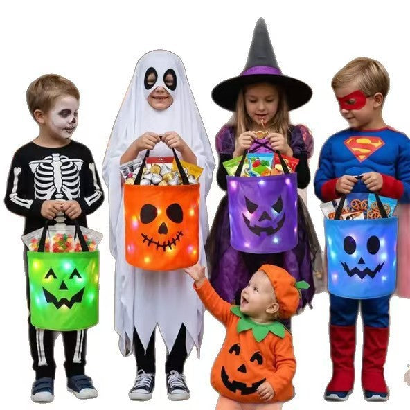 Halloween LED Glow Candy Basket, colorful cloth buckets in green, orange, purple, and blue with glowing jack-o’-lantern faces and handles