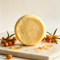 Herbal soap in a round golden-yellow bar with a smooth, subtly marbled surface and translucent edges