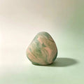 Herbal soap bar in a rounded irregular shape, with a marbled blend of pale green and pink colours