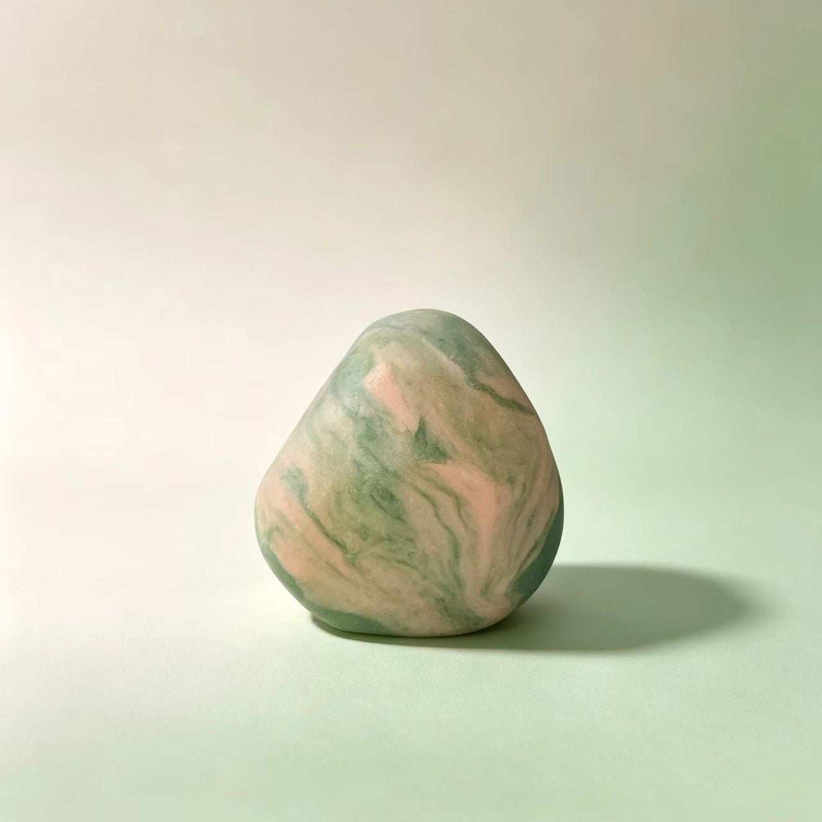 Herbal soap bar in a rounded irregular shape, with a marbled blend of pale green and pink colours