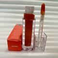 Huda Beauty Moisturizing lip gloss in a clear rectangular tube with warm amber-peach color and matching applicator