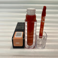Huda Beauty Moisturizing lip gloss in a clear tube with warm reddish-brown color, matching doe-foot applicator and Honey label