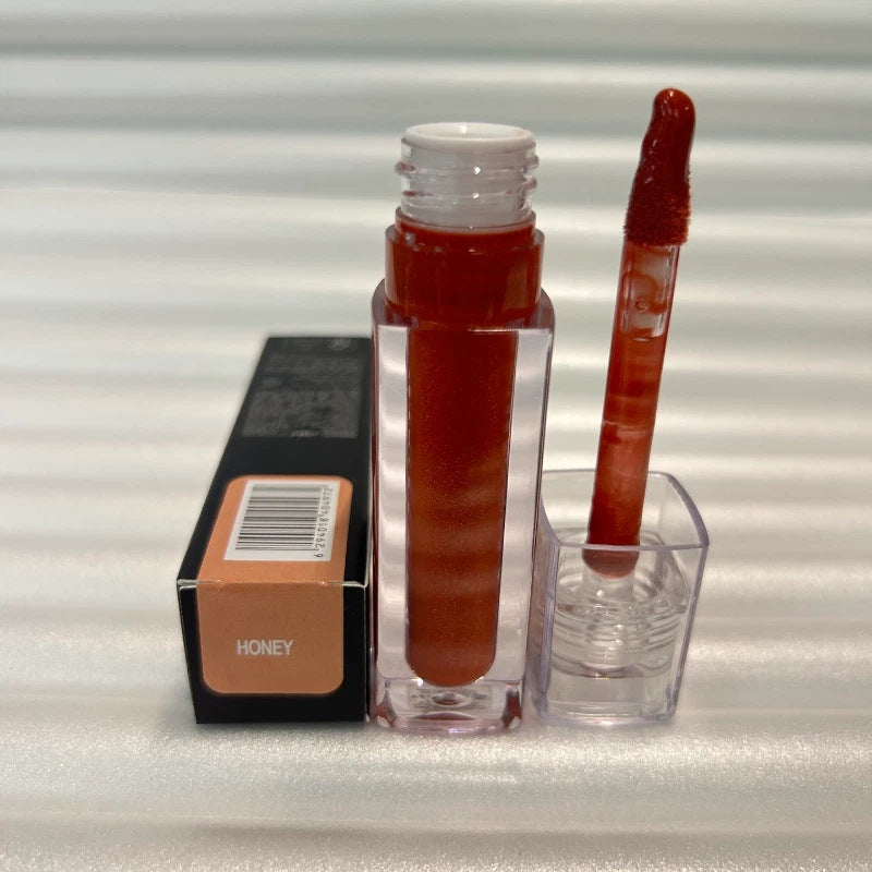 Huda Beauty Moisturizing lip gloss in a clear tube with warm reddish-brown color, matching doe-foot applicator and Honey label