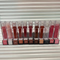 Huda Beauty Moisturizing lip gloss set in clear rectangular tubes, showing assorted pink, red, nude and brown shades with glossy color labels.