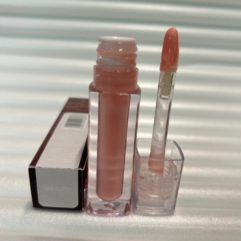 Huda Beauty Moisturizing lip gloss in a clear tube with nude pink gloss and a matching wand applicator