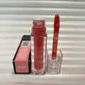 Huda Beauty Moisturizing lip gloss in a clear tube with deep rose-red gloss and matching applicator, beside its pink box