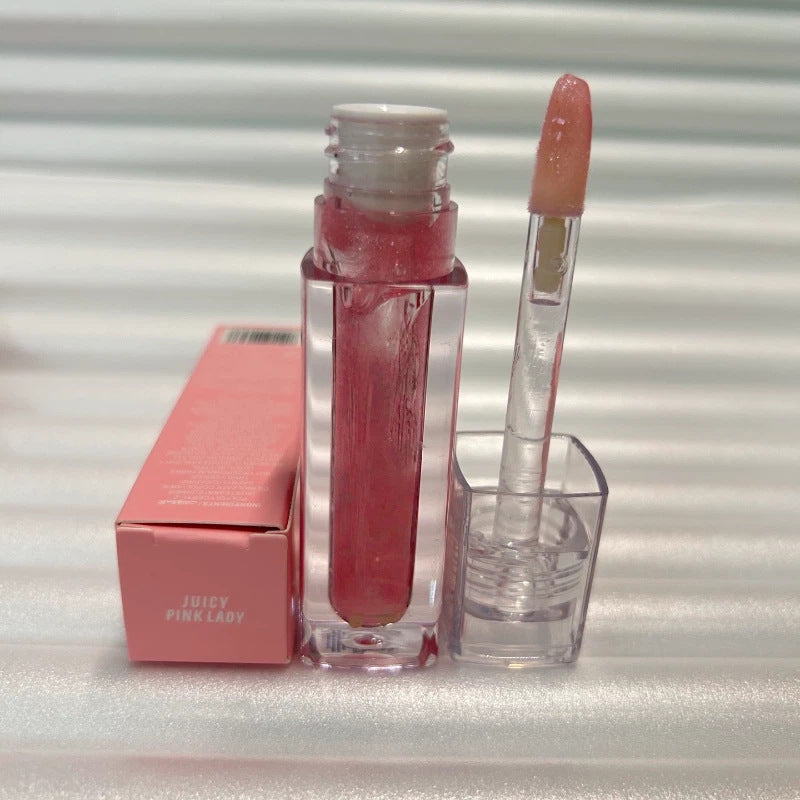 Huda Beauty Moisturizing lip gloss in a clear tube with a rosy pink shimmer, applicator wand and pink box