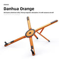Magnetic Phone Holder Stand in orange aluminum with a central magnetic disc, folding arms and black grip pads.