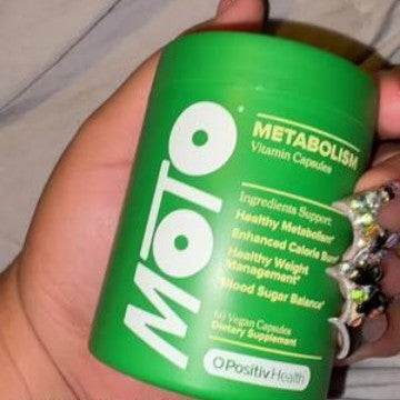 Metabolic Enhancement Capsules in a bright green plastic tub with white lettering and two dark green capsules beside it.