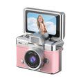 Miniature Digital Camera with a pink textured body, silver trim, prominent lens and raised flip-up display