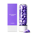 Purple Toothpaste Tablets in compact purple-and-white packaging with a clear cylinder of round tablets and two loose tablets
