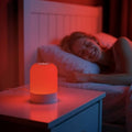 Red Light Therapy Lamp with a glowing red cylindrical shade, silver base, and compact touch-control design
