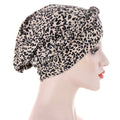 Short braids can be hidden beneath a beige polyester headscarf cap with a dense black leopard print and gathered crown