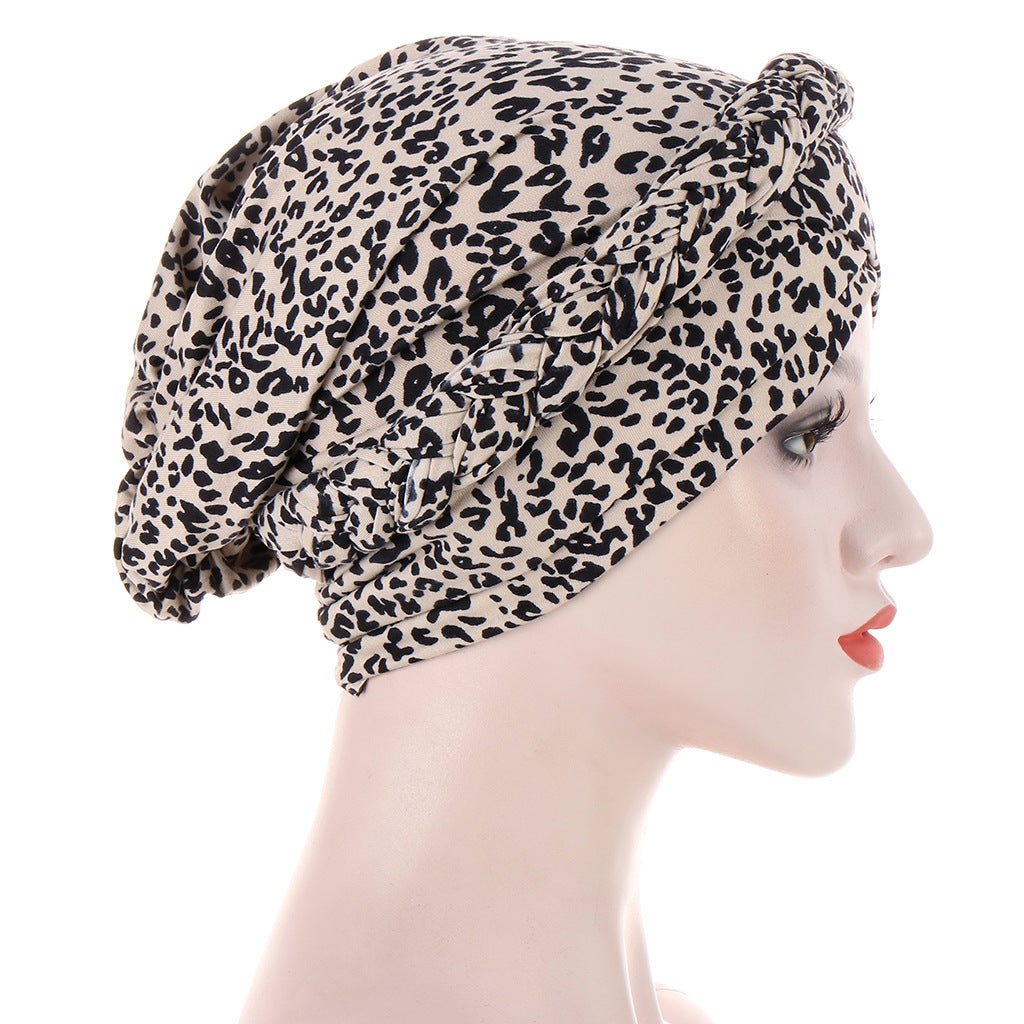 Short braids can be hidden beneath a beige polyester headscarf cap with a dense black leopard print and gathered crown