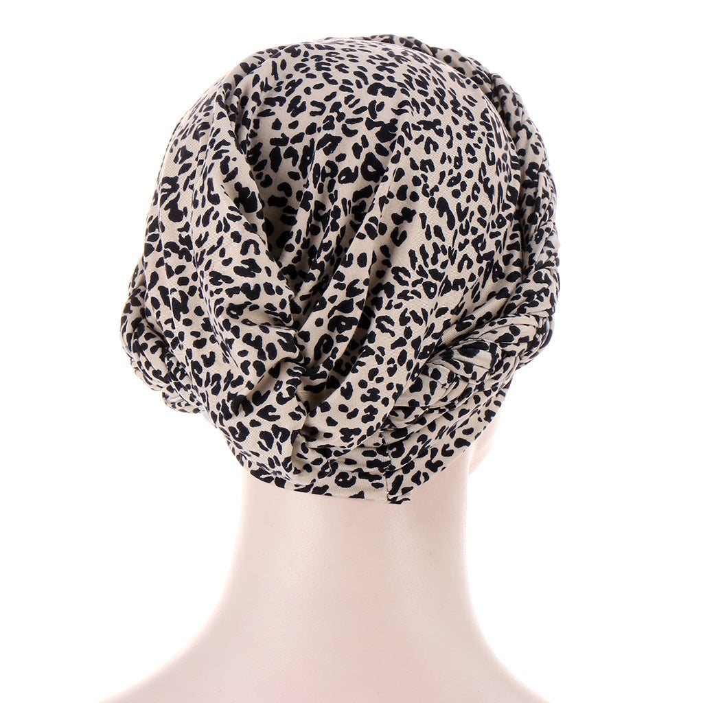 Printed headscarf cap in beige polyester with dense black leopard spots and gathered fabric; Short braids can be hidden beneath it.