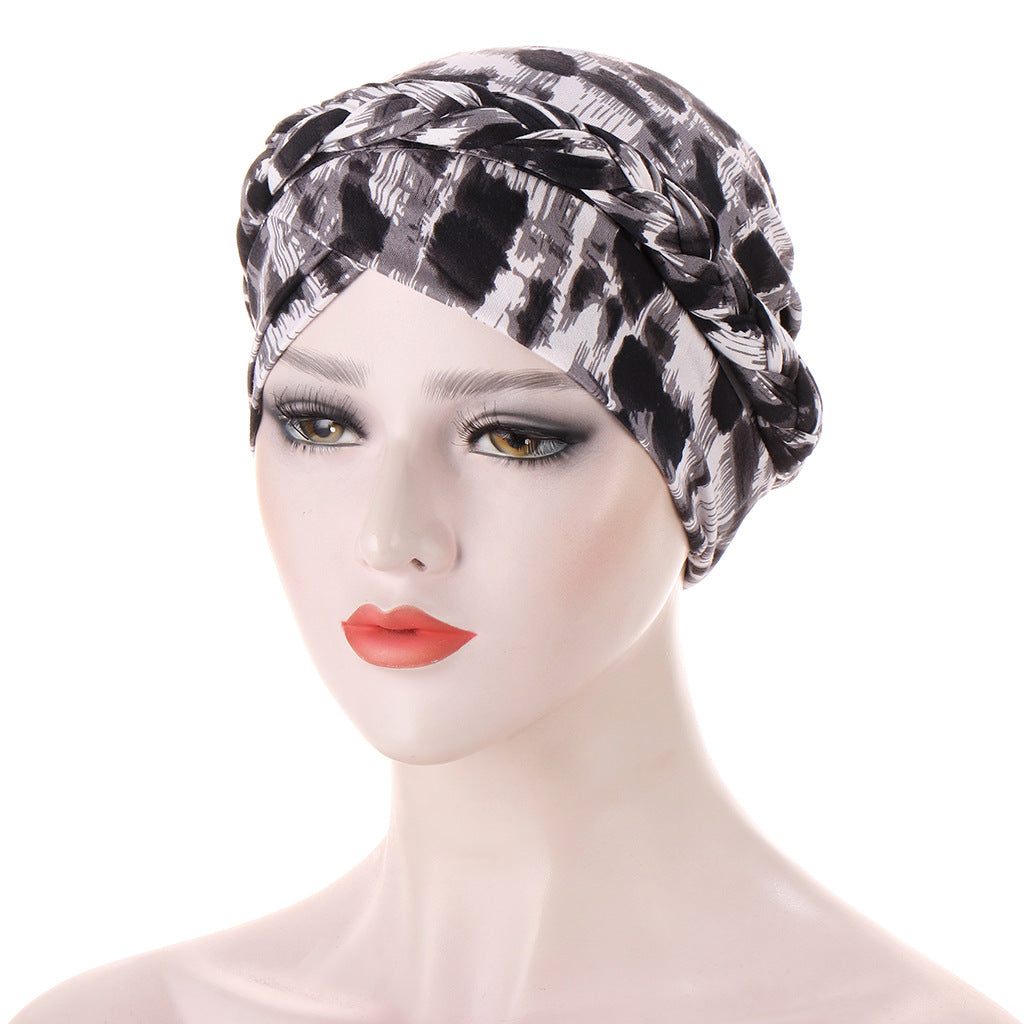 Headscarf cap with a black, gray, and white abstract print, featuring braided trim around the crown; Short braids can be hidden