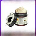 Tallow Honey Cream in an open dark amber jar, showing pale whipped balm and a cream label with a black animal silhouette