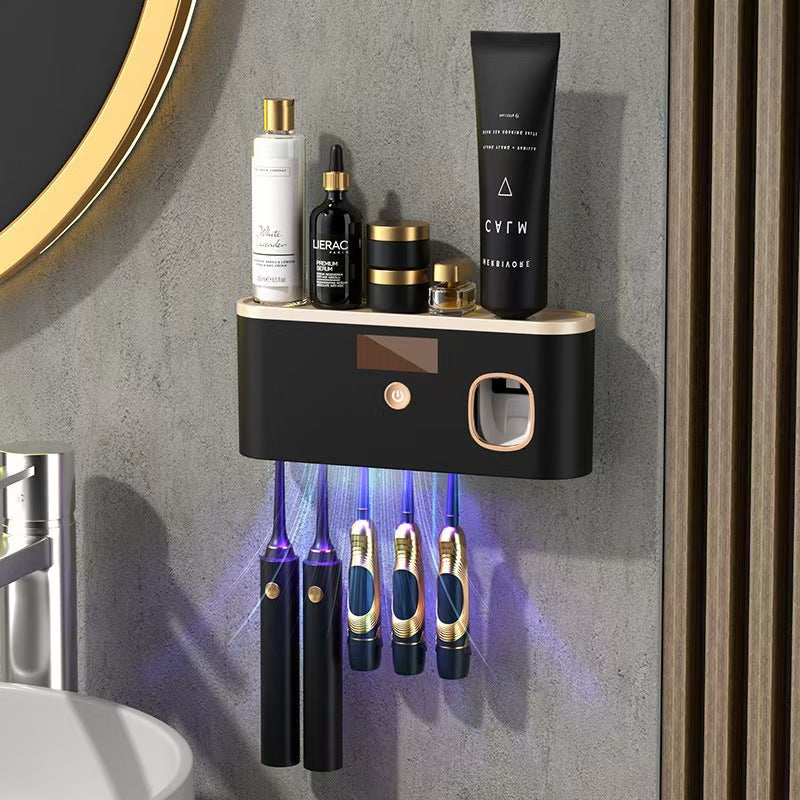 UV Sterilizing Toothbrush Holder in black with gold trim, a button, display and hanging toothbrush slots beneath a shelf