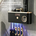 UV Sterilizing Toothbrush Holder in black plastic with gold trim, glowing power button and blue UV light over stored toothbrushes