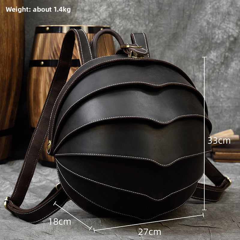 Backpack in dark brown genuine leather with a rounded beetle-inspired shape, layered curved panels and contrast stitching