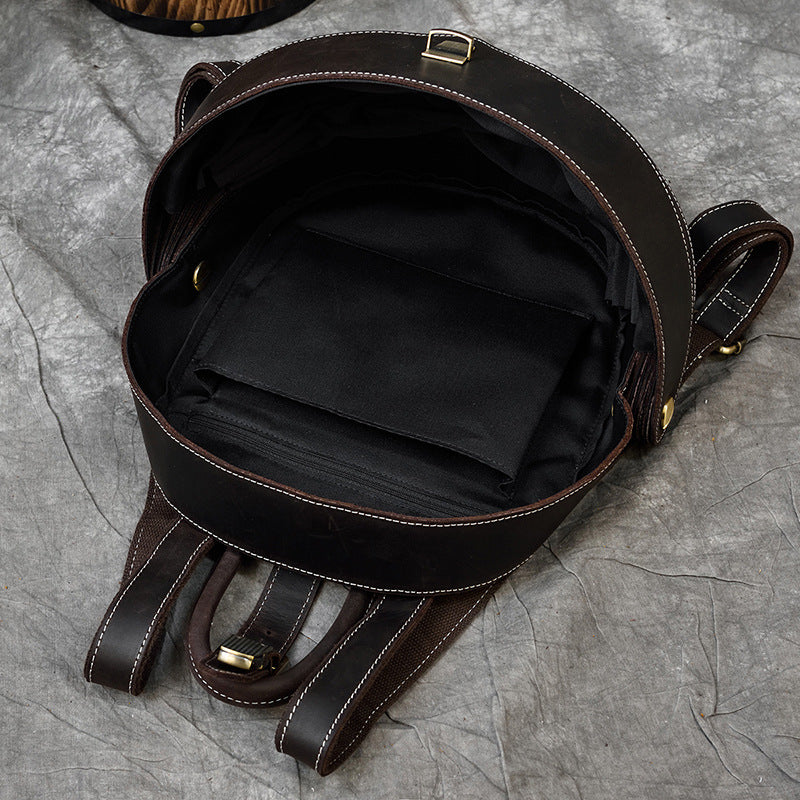 Vintage Genuine Leather backpack in dark brown cowhide, shown open with black fabric lining, stitched edging and metal buckle details