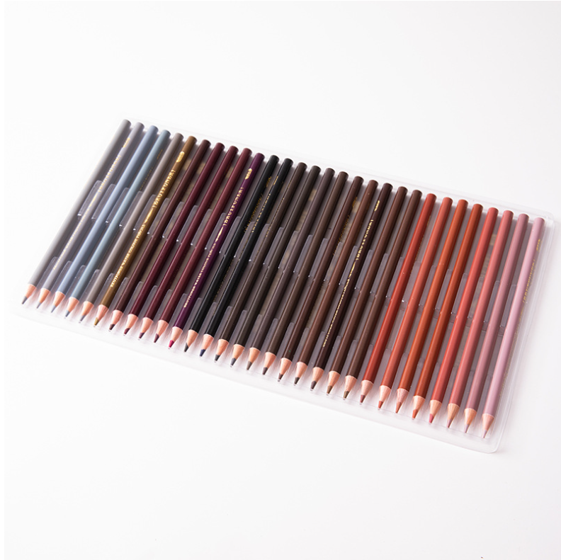 Water-Soluble Colored Pencils arranged in a clear tray, with wooden barrels in muted gray, brown, red, and pink shades